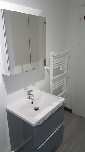 A bathroom with a white sink, a mirror, and a towel rack.