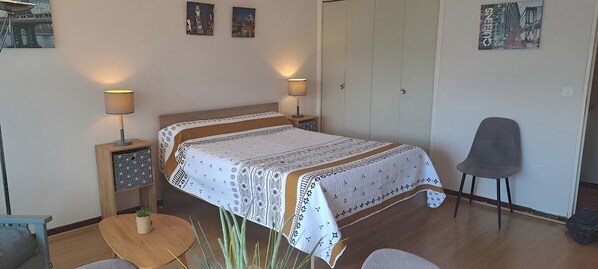 A bedroom with a bed, bedside lamps, a chair, and artwork on the walls.