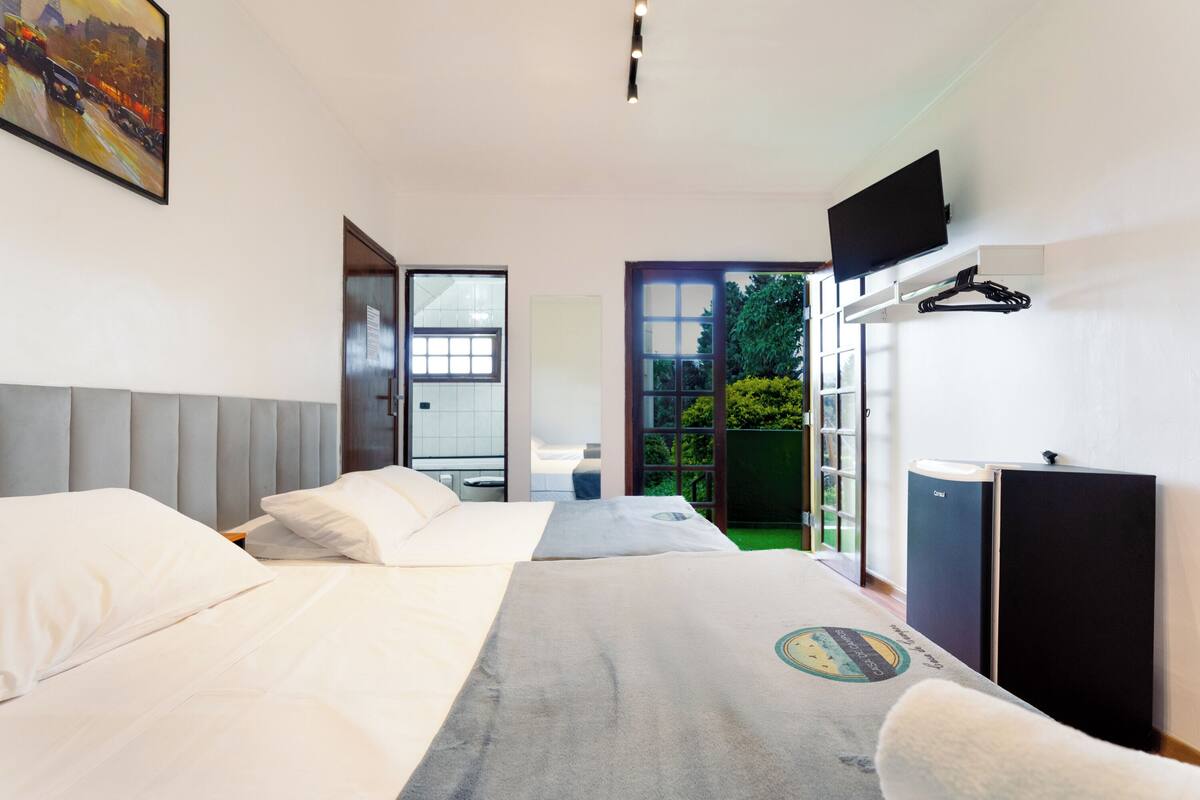 Een moderne hotelkamer met twee bedden, een flatscreen televisie en uitzicht op het groen.