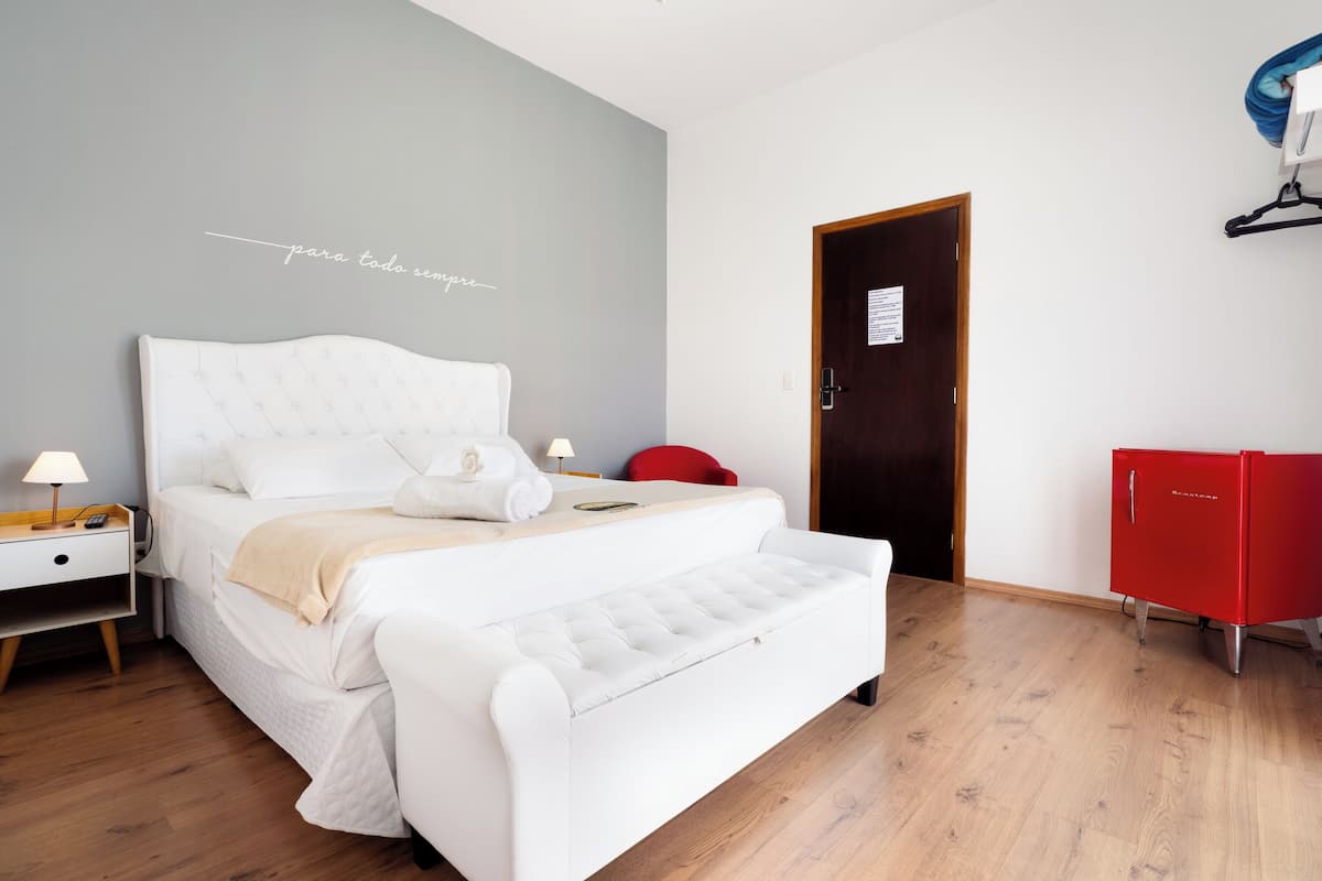 Een slaapkamer met een bed, nachtkastje, lamp en een rode kast.