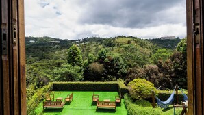 A view from a room with a green artificial lawn, two wooden benches, and a hammock. - Pousada Casa de Campos Mountain by Concavus (Campos do Jordão)