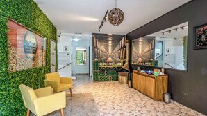 A hotel lobby with a green wall, a reception desk, and a seating area with yellow chairs. - Pousada Casa de Campos Mountain by Concavus (Campos do Jordão)