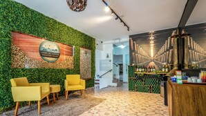 A reception area with a green wall, wooden reception desk, and yellow chairs. - Pousada Casa de Campos Mountain by Concavus (Campos do Jordão)