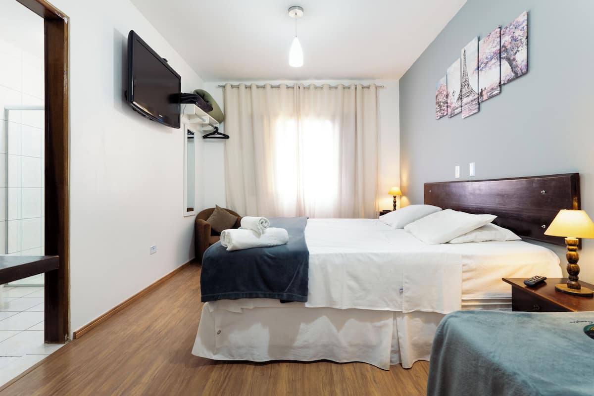 Een hotelkamer met een bed, nachtkastje, lamp en kunst aan de muur.