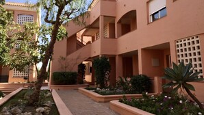 Un edificio de varios pisos con balcones, un patio con plantas y un cielo despejado.