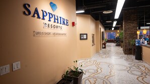 Um corredor com uma placa indicando Sapphire Resorts, piso de azulejos e plantas em vasos.