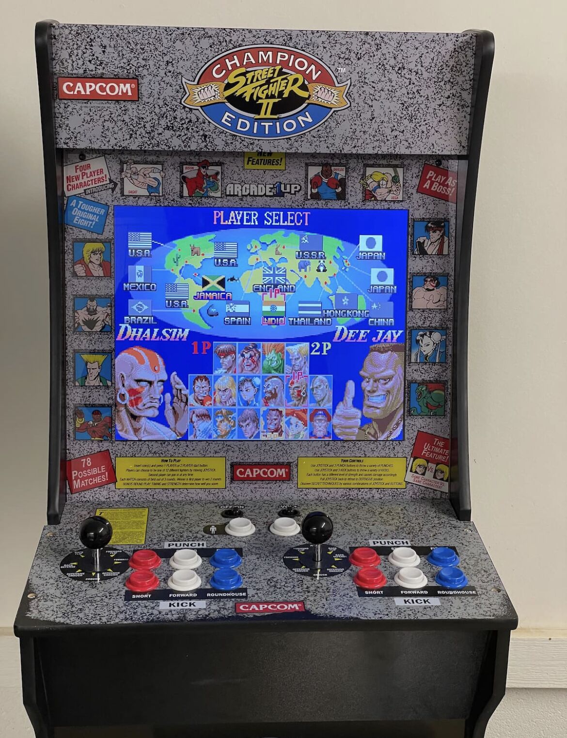 Una macchina arcade di Street Fighter II di Capcom con schermata di selezione, icone dei personaggi e pulsanti di controllo.