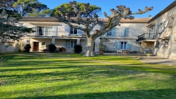A courtyard with a well-maintained lawn, a tree, and a building with multiple windows and balconies. - Mas de Barthe (Avignon)