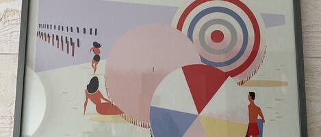 A framed poster with a beach scene, windmills, and people.
