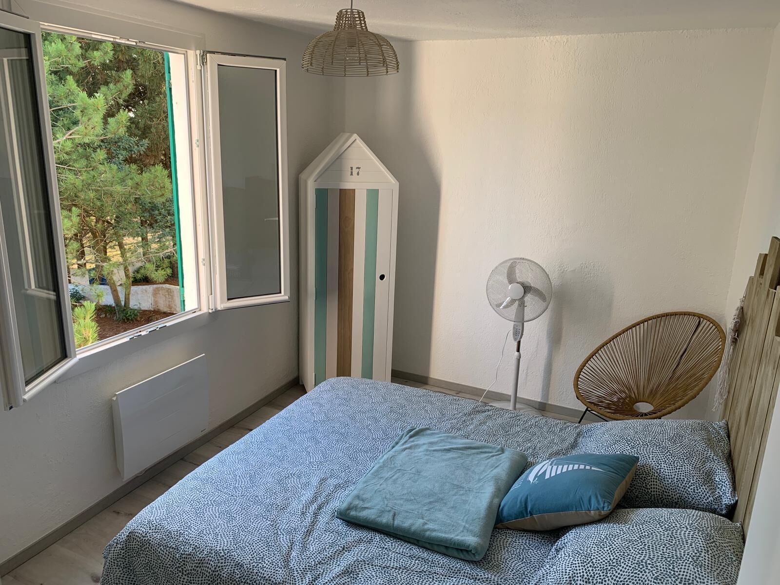 Un dormitorio con cama, ventilador, silla y armario.