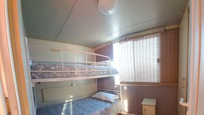 A compact room with bunk beds, a small cabinet, and a window with blinds. - Casa La Abuela María (Vejer de la Frontera)