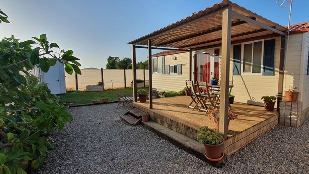 A mobile home with a wooden deck, outdoor seating, and potted plants. - Casa La Abuela María (Vejer de la Frontera)