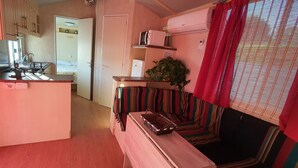 A compact living space with a kitchenette, a striped sofa, and a small dining table. - Casa La Abuela María (Vejer de la Frontera)