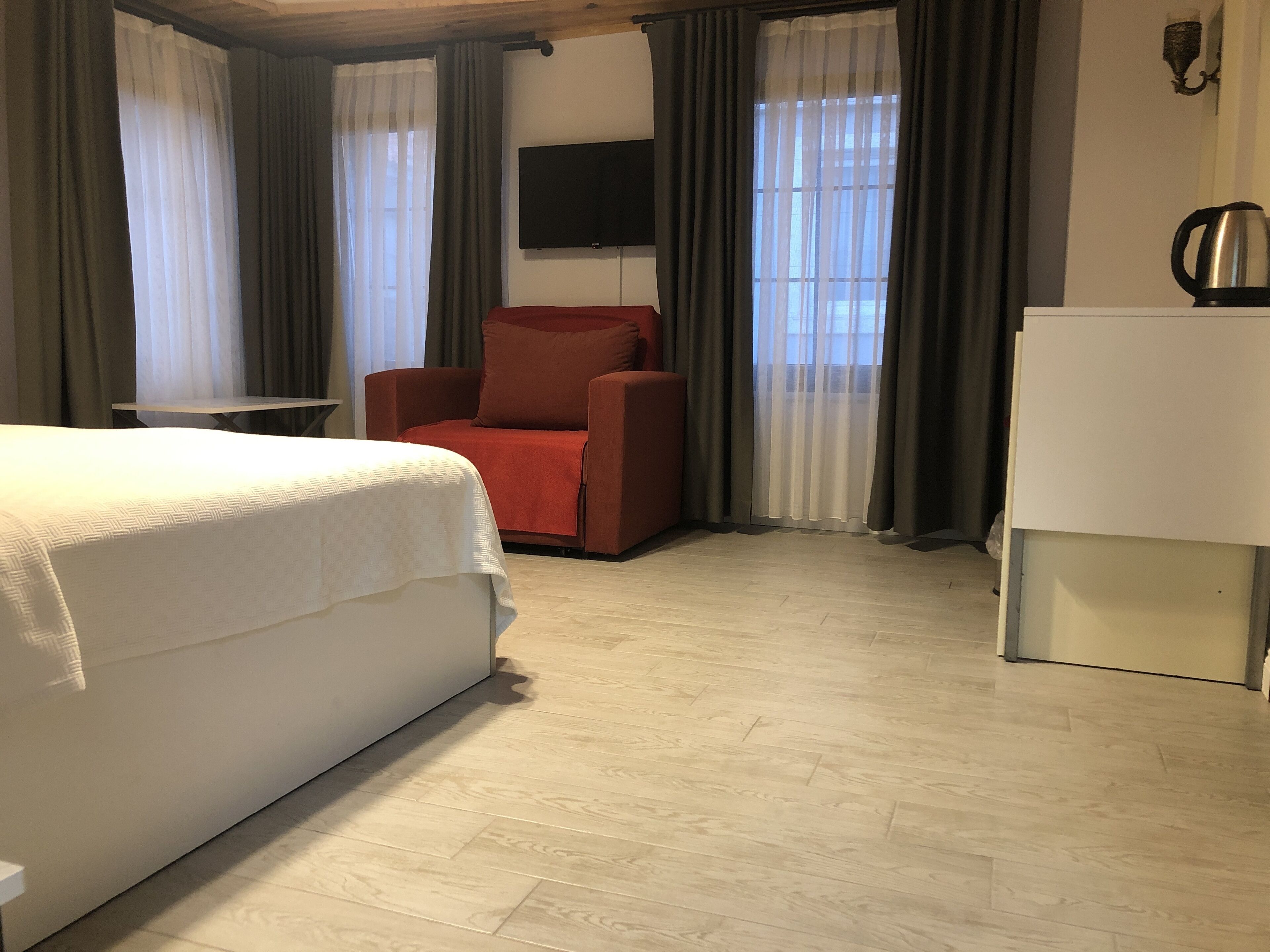 Una habitación de hotel con una cama, un sillón rojo, un televisor y una cafetera.