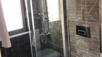 A bathroom with a glass-enclosed shower, a toilet, and a patterned wall.