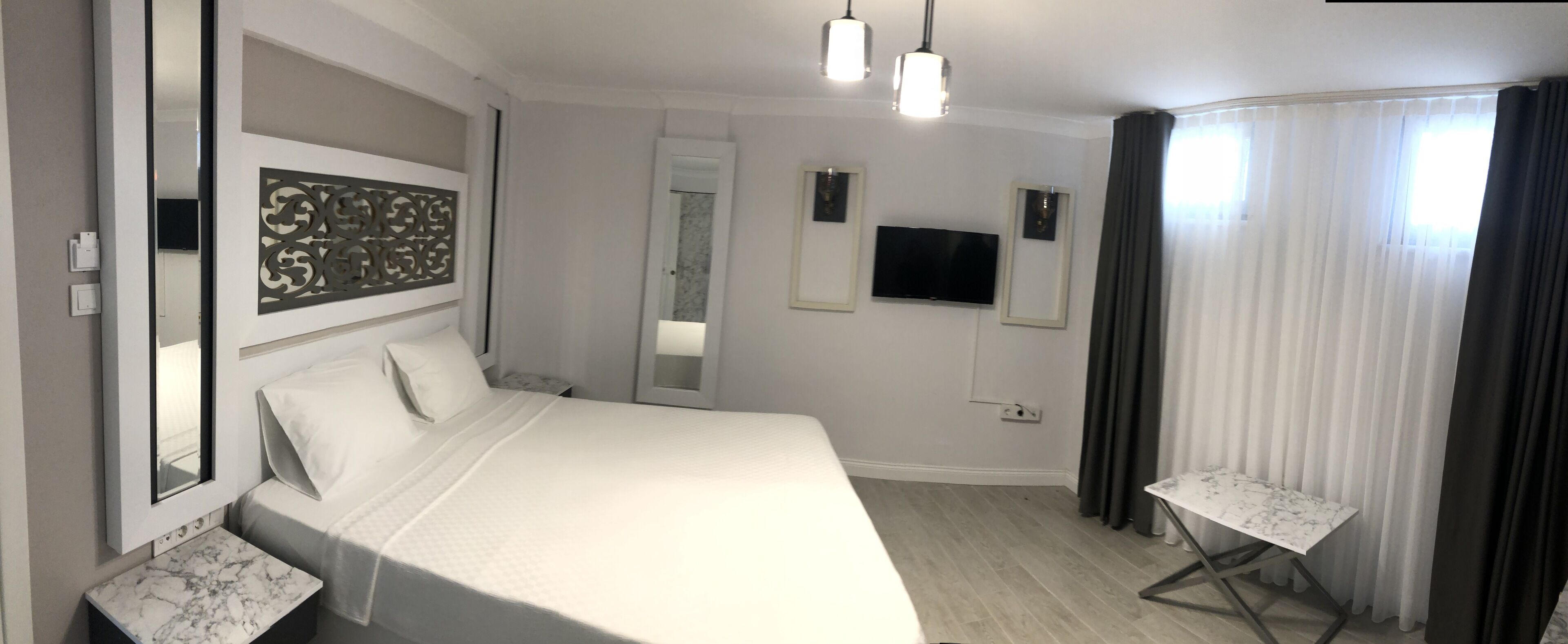 Ein Hotelzimmer mit einem großen Bett, einem kleinen Tisch, einem Fernseher und einem Spiegel.