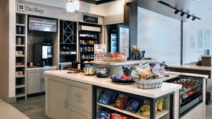 Ein modernes Café-Interieur mit einer Theke, Regalen voller Snacks und einer Kühlvitrine.