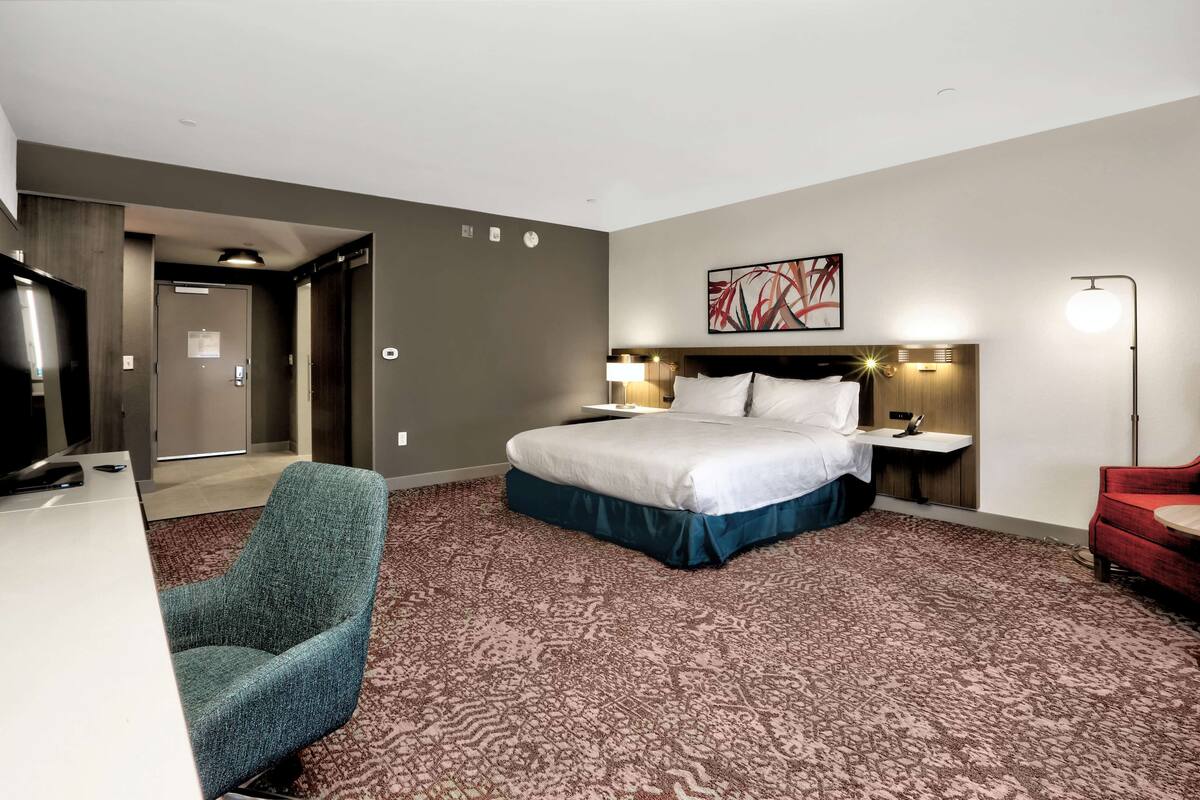 Hotellihuone, jossa on suuri sänky, työpöytä, tuoli ja punainen sohva.