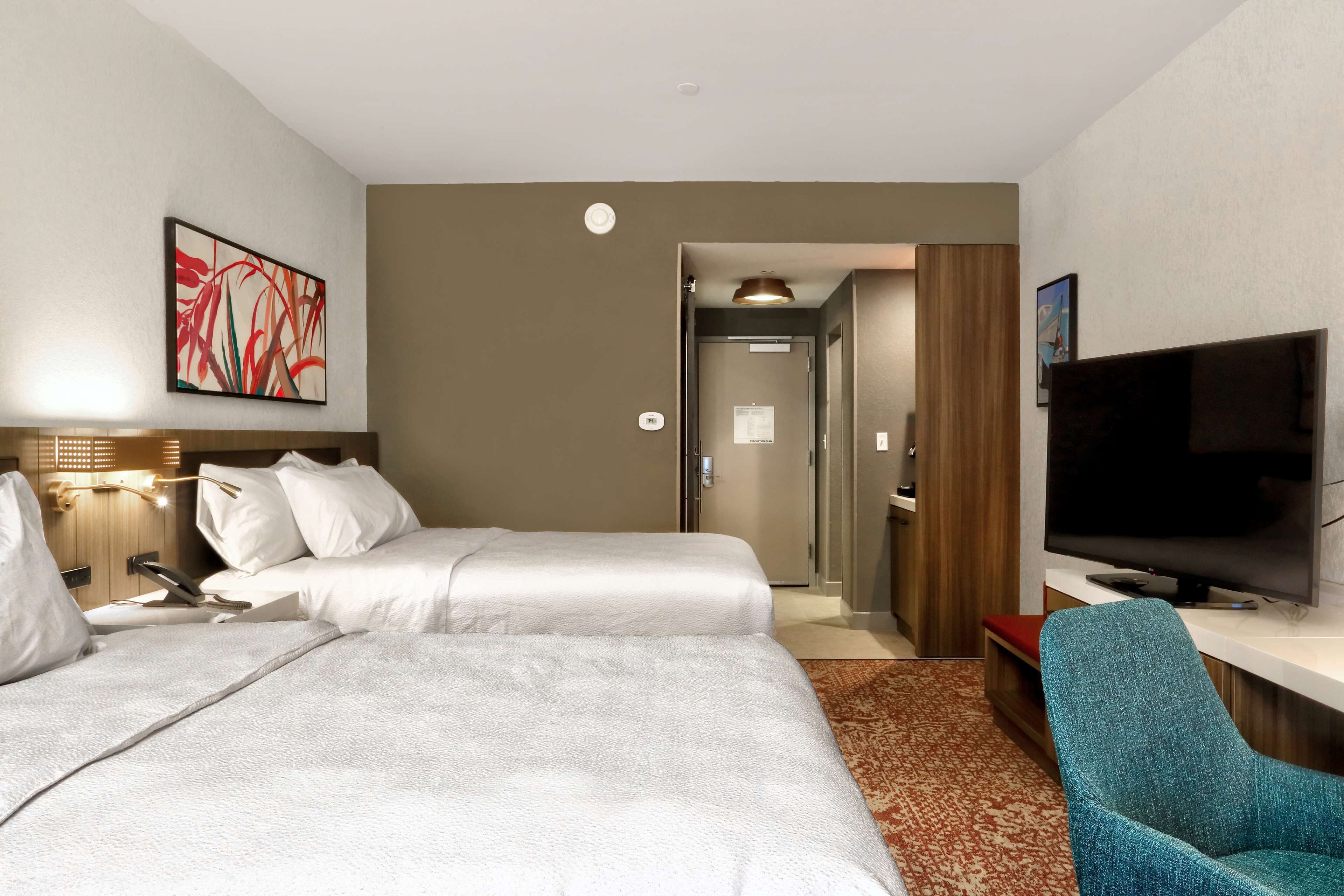 A hotel room with two beds, a television, a desk, and a chair.