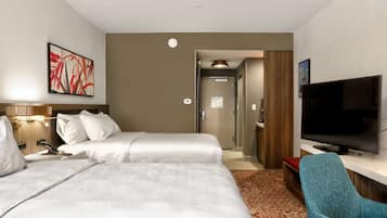 Una habitación de hotel con dos camas, televisión, escritorio y una silla.