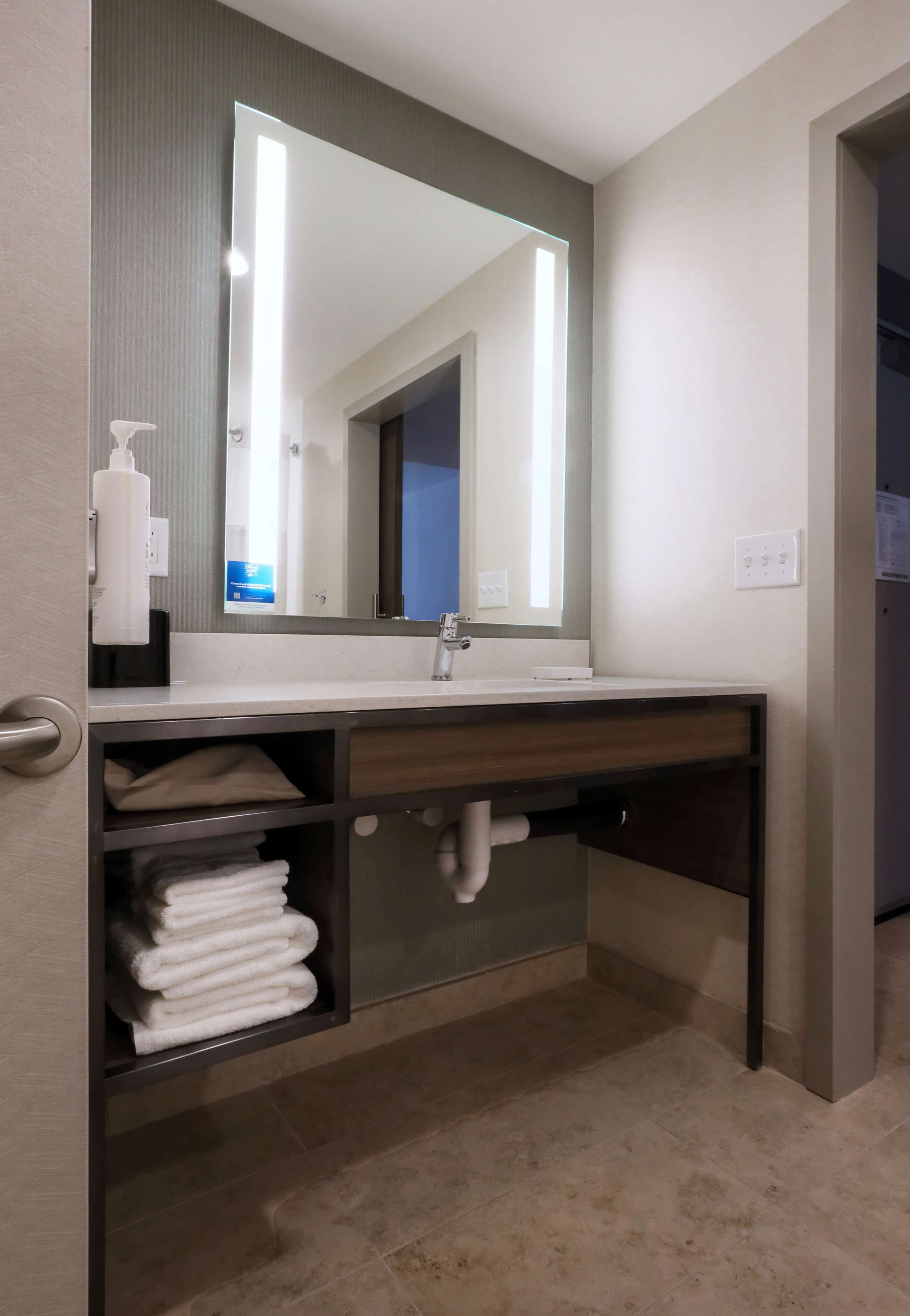A bathroom with a sink, mirror, towel rack, and a door.