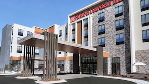 Ein modernes Hotel mit einer Stein-Fassade, einem markanten Eingangsvordach und einem gut sichtbaren Hilton Inn Schild.
