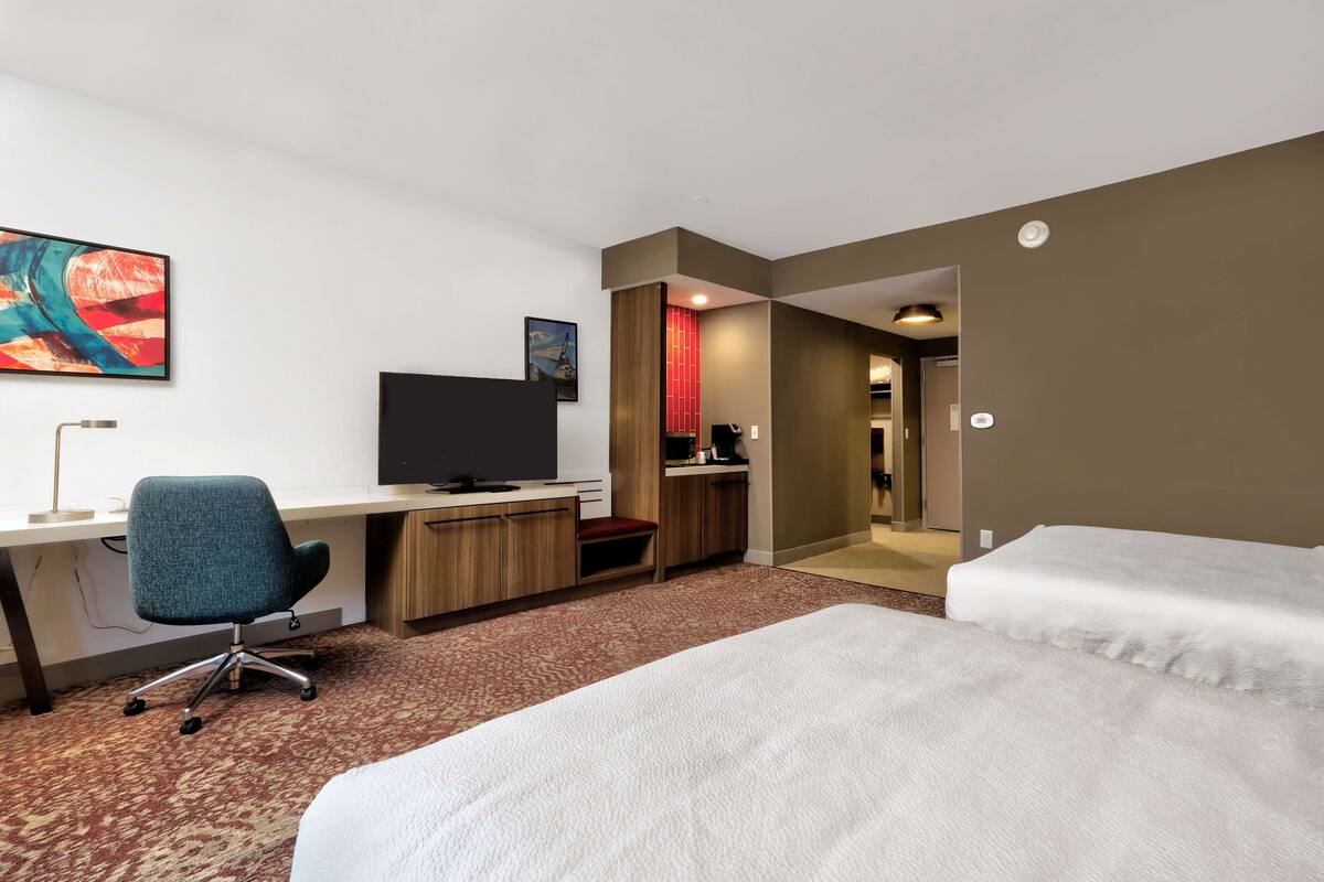 Hotellihuone, jossa on työpöytä, tuoli, sänky ja televisio.