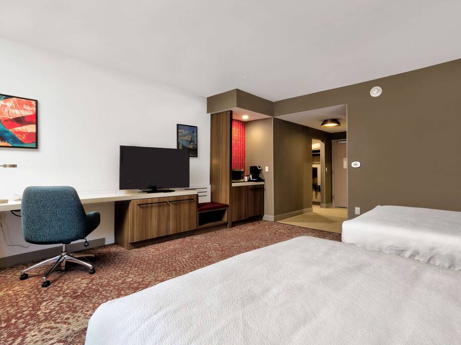 Une chambre d’hôtel équipée d’un bureau, d’une chaise, d’un lit et d’une télévision.