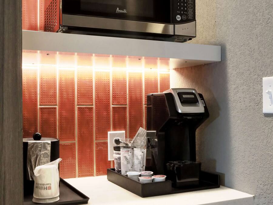 Uma cozinha com micro-ondas, cafeteira e chaleira no balcão.
