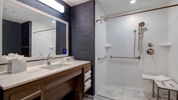 Un baño moderno con lavamanos dobles, un espejo grande y una ducha a ras de suelo con cabezal de ducha manual.