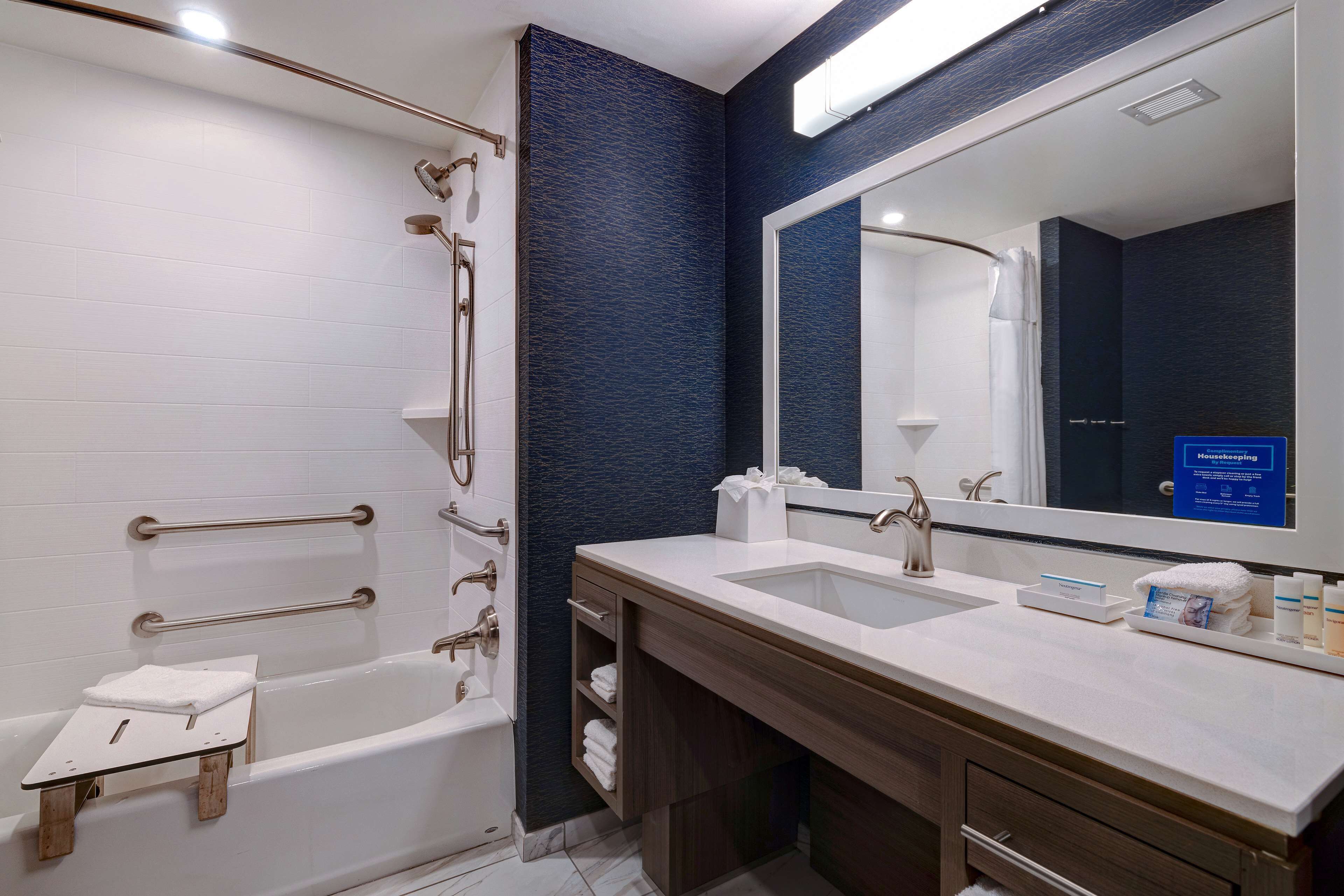 A modern bathroom with a bathtub, a shower, a vanity with a sink, and a large mirror.