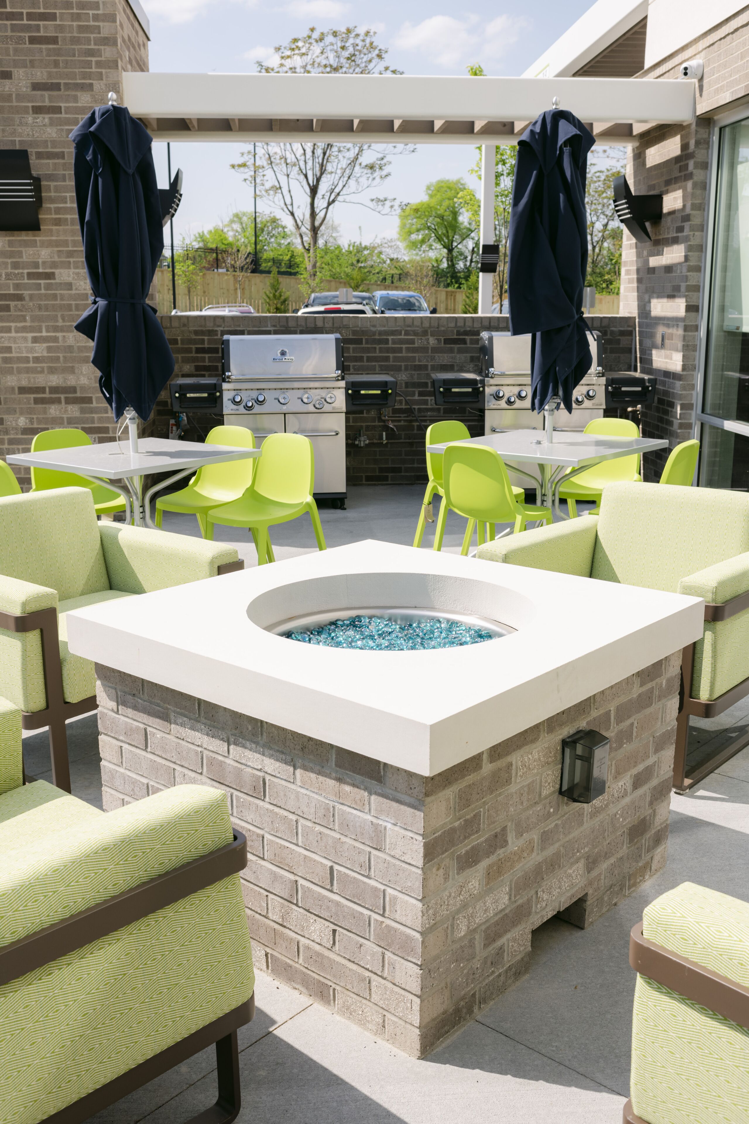 An outdoor patio with a barbecue grill, seating area, and a built-in fire pit.