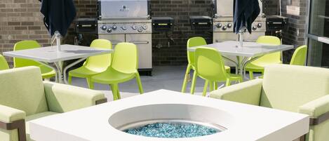 An outdoor patio with a barbecue grill, seating area, and a built-in fire pit.