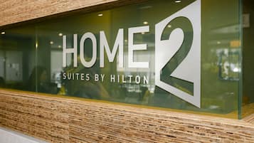 A glass window with the text "HOME 2 SUITES BY HILTON" indicating a specific hotel suite location.