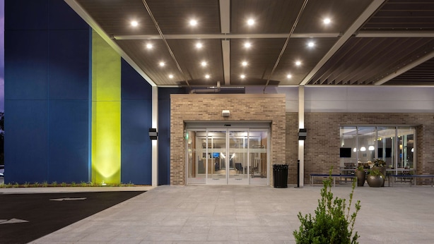 A modern building entrance with glass doors, a brick facade, and a flat roof with recessed lighting. - Home2 Suites Downtown Nashville/Metrocenter (Nashville)