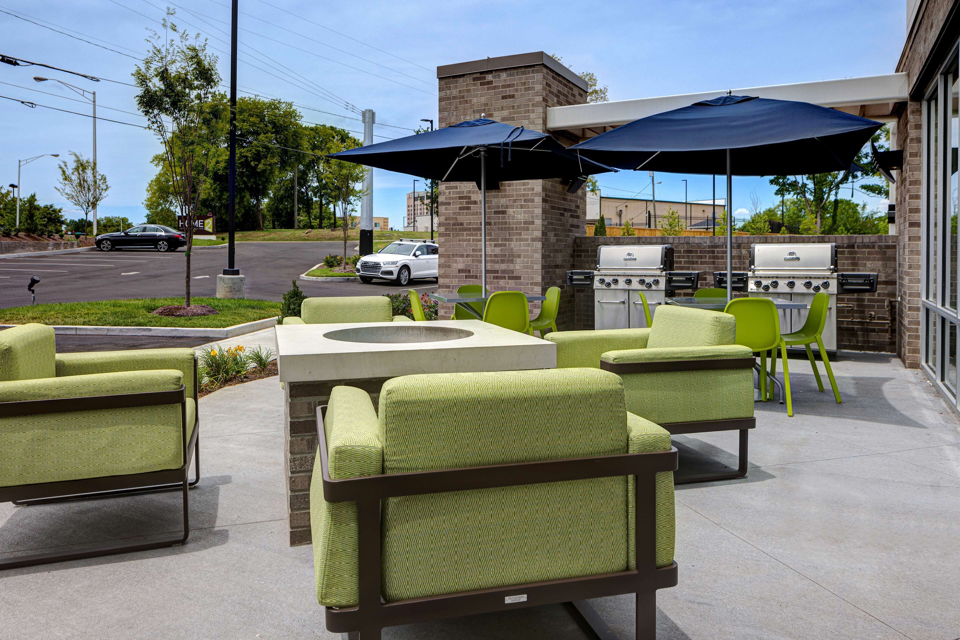 An outdoor patio with green chairs and a grill area.
