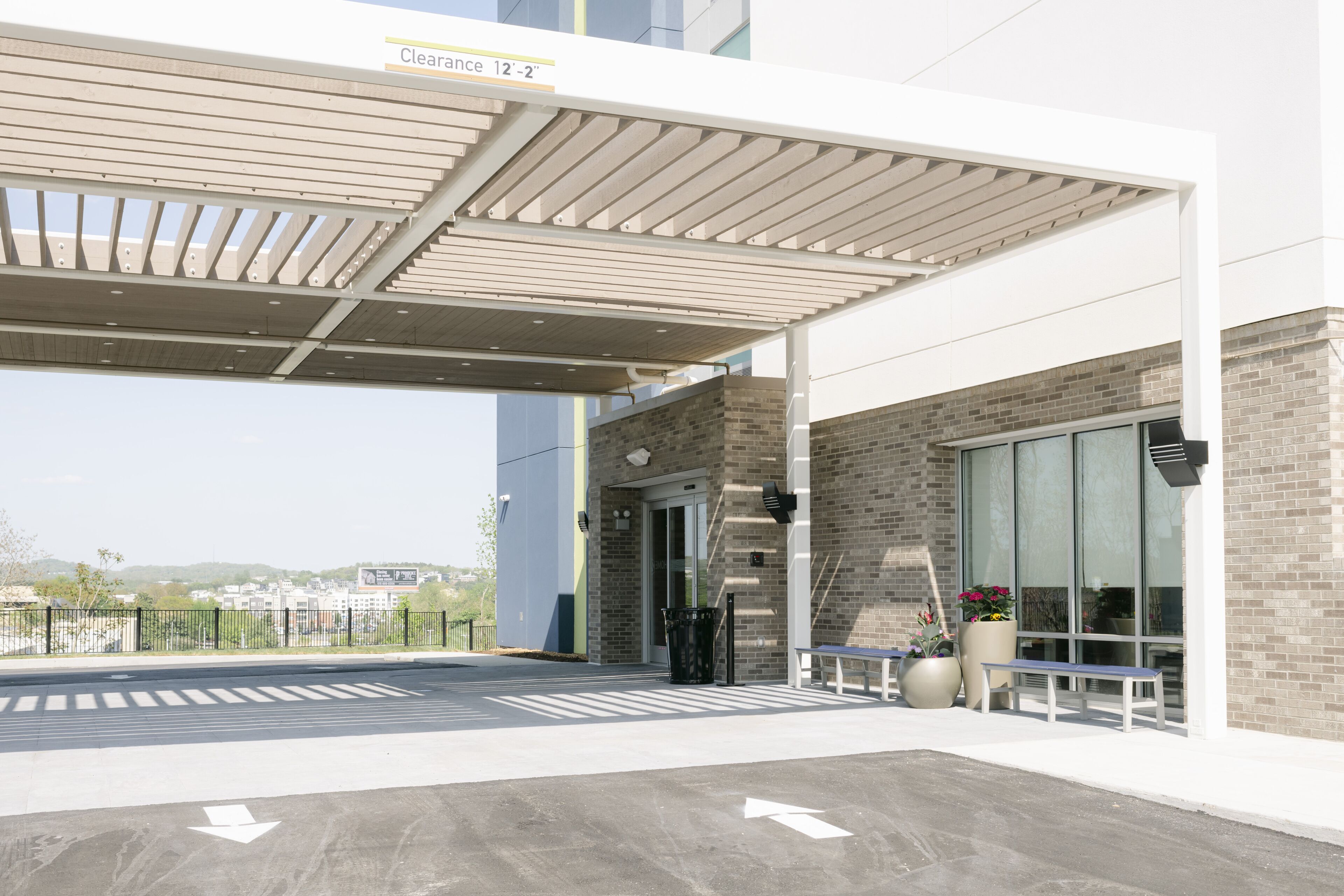 A covered outdoor area with a clear path, a bench, and a trash bin.