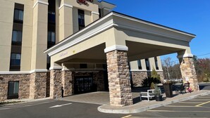 Un hotel Hampton Inn amb façana de pedra, entrada coberta i una zona d'aparcament.