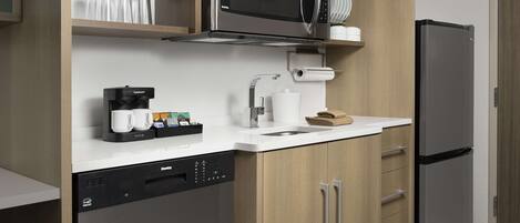 A modern kitchen with a built-in dishwasher, a coffee maker, a microwave, and a refrigerator.