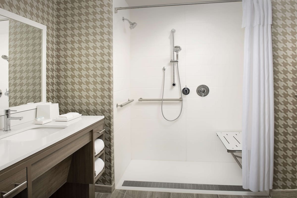 Een moderne badkamer met een douche, wastafel en badmeubel.