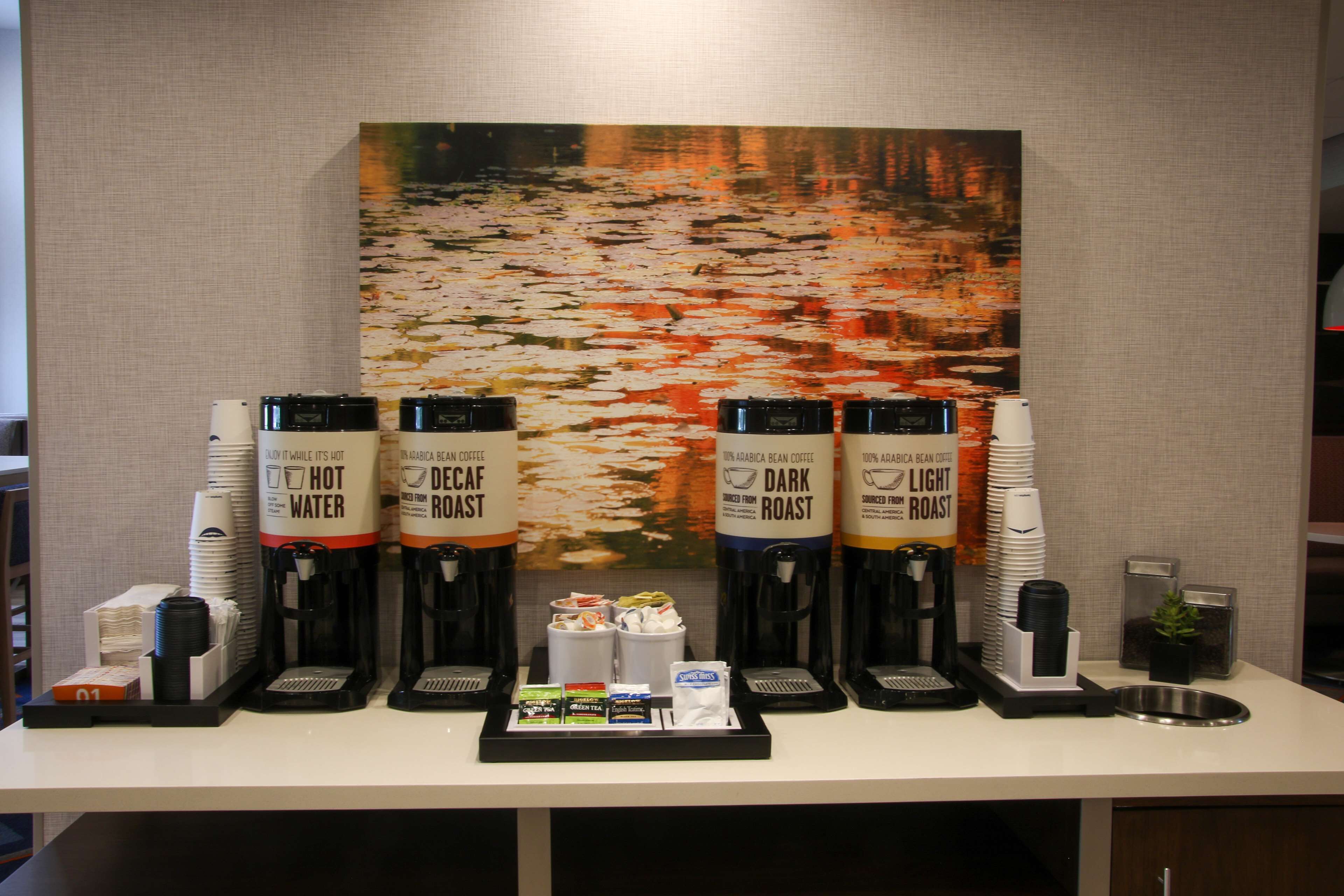 En kaffestation med fyra kaffedispensrar märkta med ”varmt vatten”, ”kaffe utan koffein”, ”mörkrostat kaffe” och ”ljusrostat kaffe”.