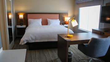 A hotel room with a bed, bedside tables with lamps, a desk with a chair, and a TV.