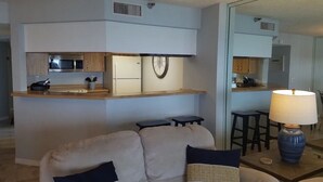 Un espacio habitable pequeño con kitchenette, un sofá y una lámpara.