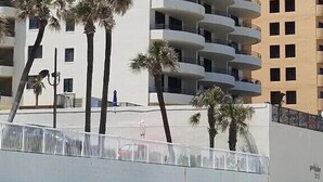Un hotel de varios pisos con una fachada curva, balcones en cada planta y palmeras en primer plano.