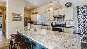A modern kitchen with a large island, bar stools, and various appliances.