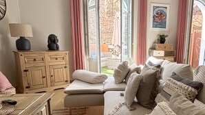 A cozy living room with a sofa, a wooden cabinet, a lamp, and a patterned rug. - "La Calade" Villa les glycines (Collioure)