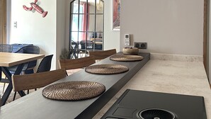 A modern kitchen with a long countertop, woven placemats, and a built-in stove. - "La Calade" Villa les glycines (Collioure)