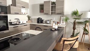 A modern kitchen with a central island, built-in appliances, and a bar area with stools. - "La Calade" Villa les glycines (Collioure)