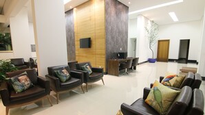 Un moderno vestíbulo de hotel con sofás de cuero, un mostrador de recepción y un televisor de pantalla plana.