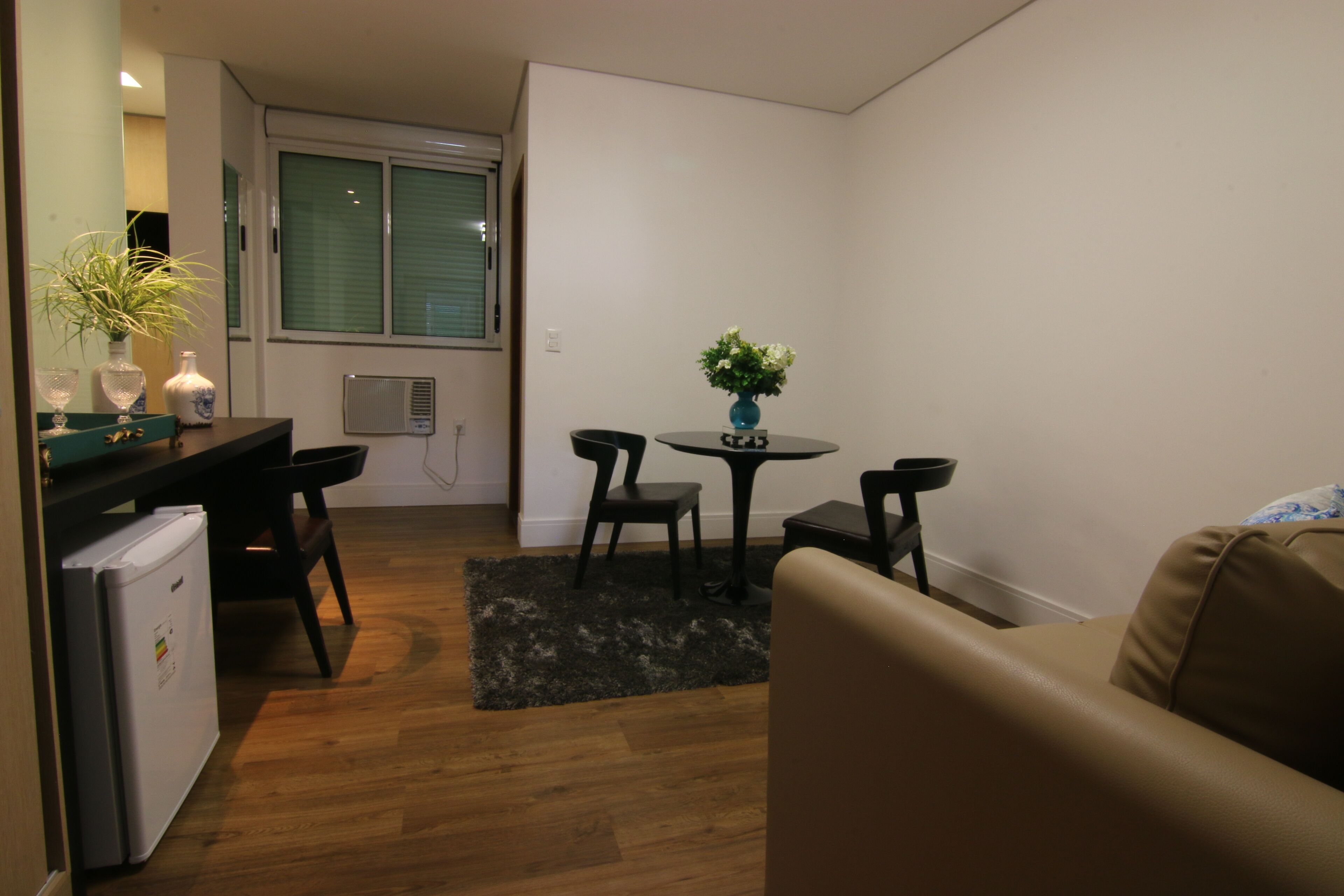 A compact living space with a kitchenette, a dining area with a small table and chairs, and a sofa.
